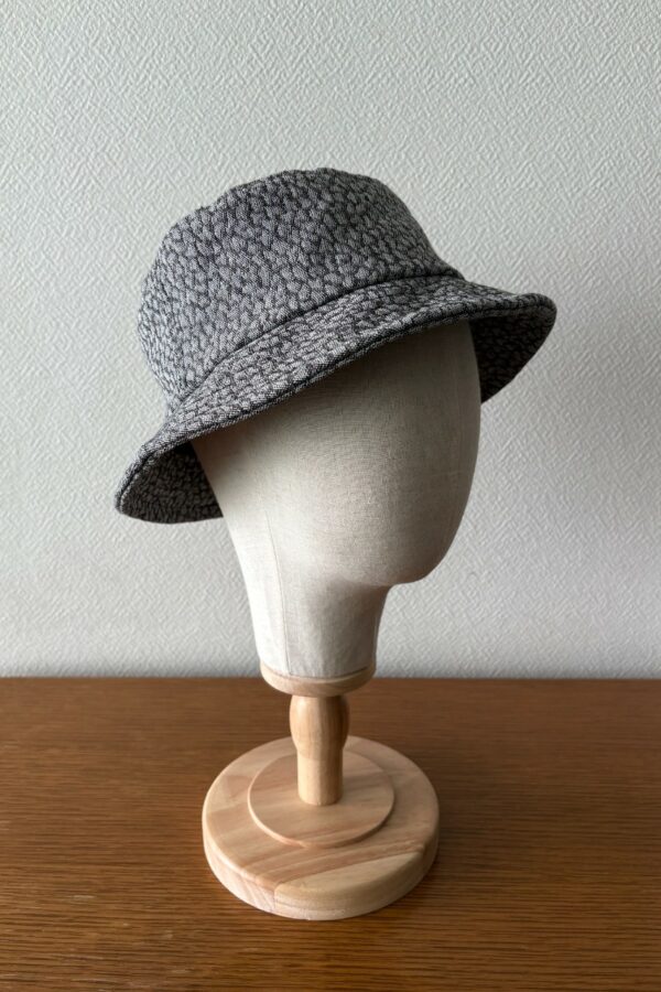 Bob unisexe gris foncé vu de face avec motif de petites taches irrégulières gris clair.